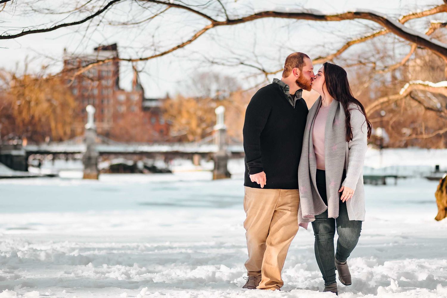 A quick kiss at sunset whiling strolling through the Boston Public Garden in winter during their engagement session