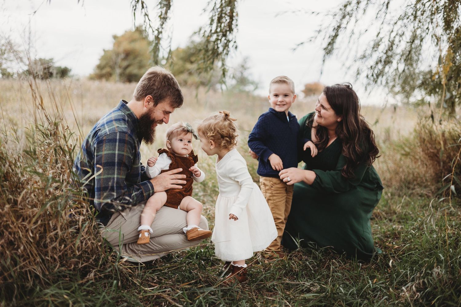 Family taking photos together in a blooming wildflower field at sunset.