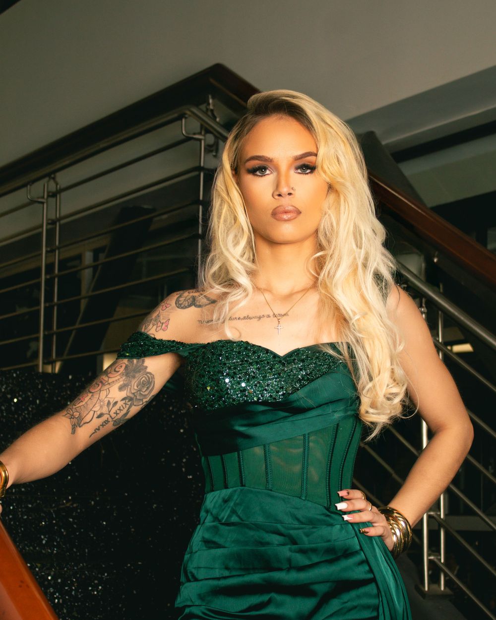 Glamorous photo of someone in an emerald green sequined dress posing on stairs.