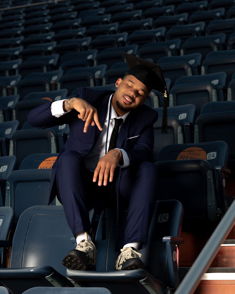 Artistic graduation photo taken in stadium seating area with navy suit.