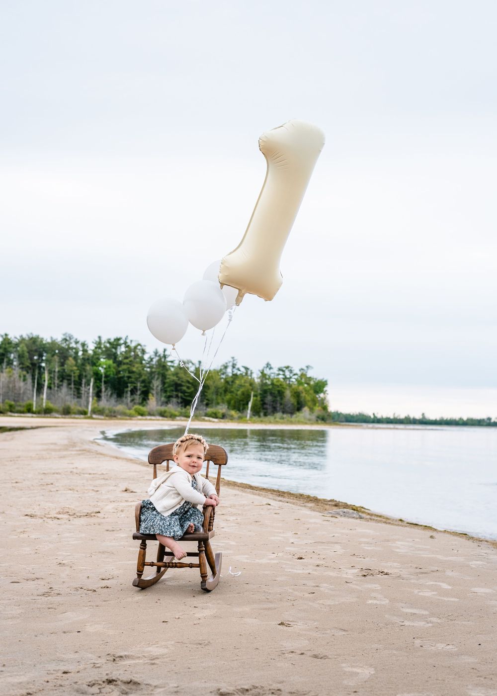 A series of four connected beach photos showing a toy wagon with white balloons against a scenic waterfront backdrop.