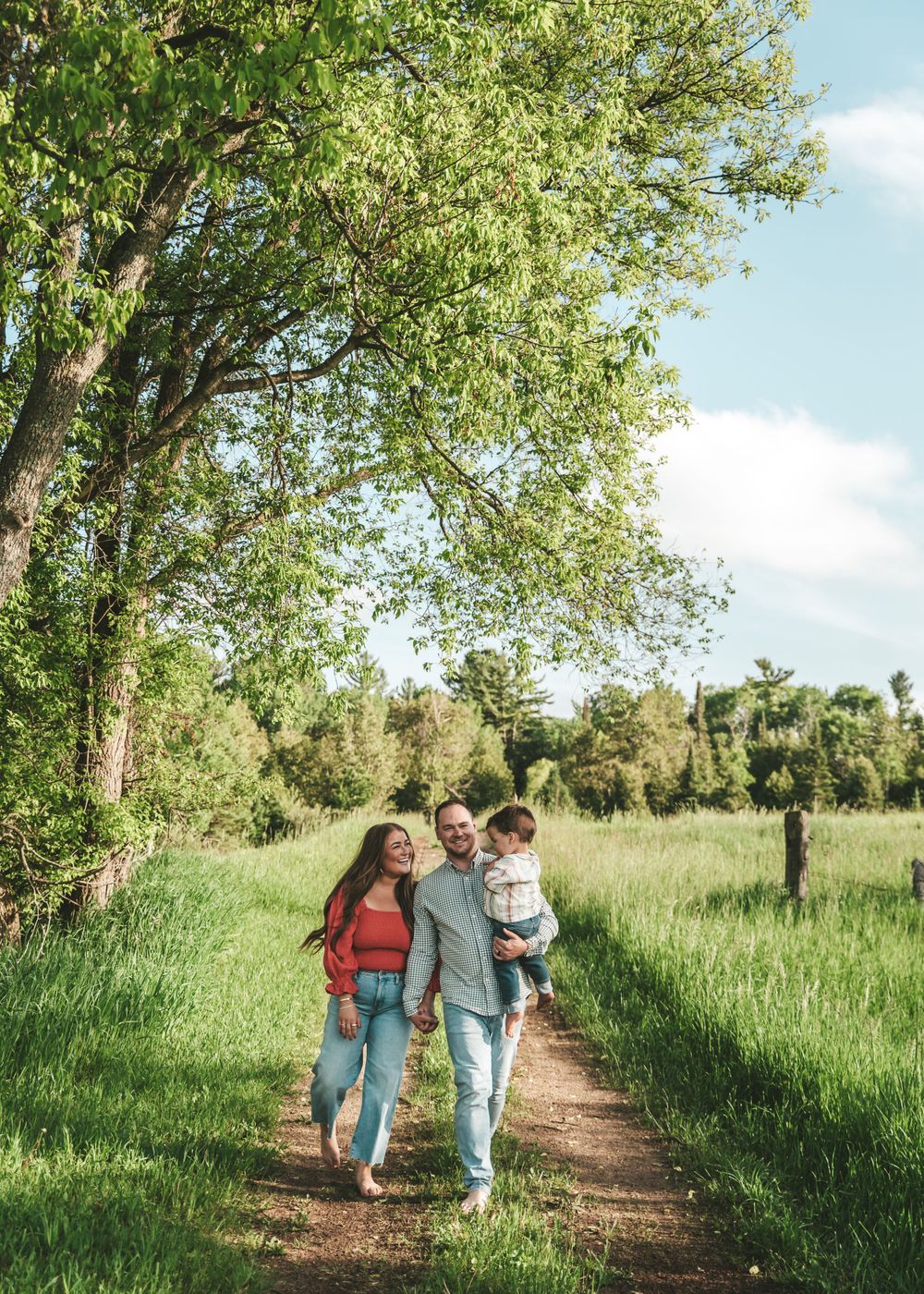 Family walking together on trail through lush green summer meadow.