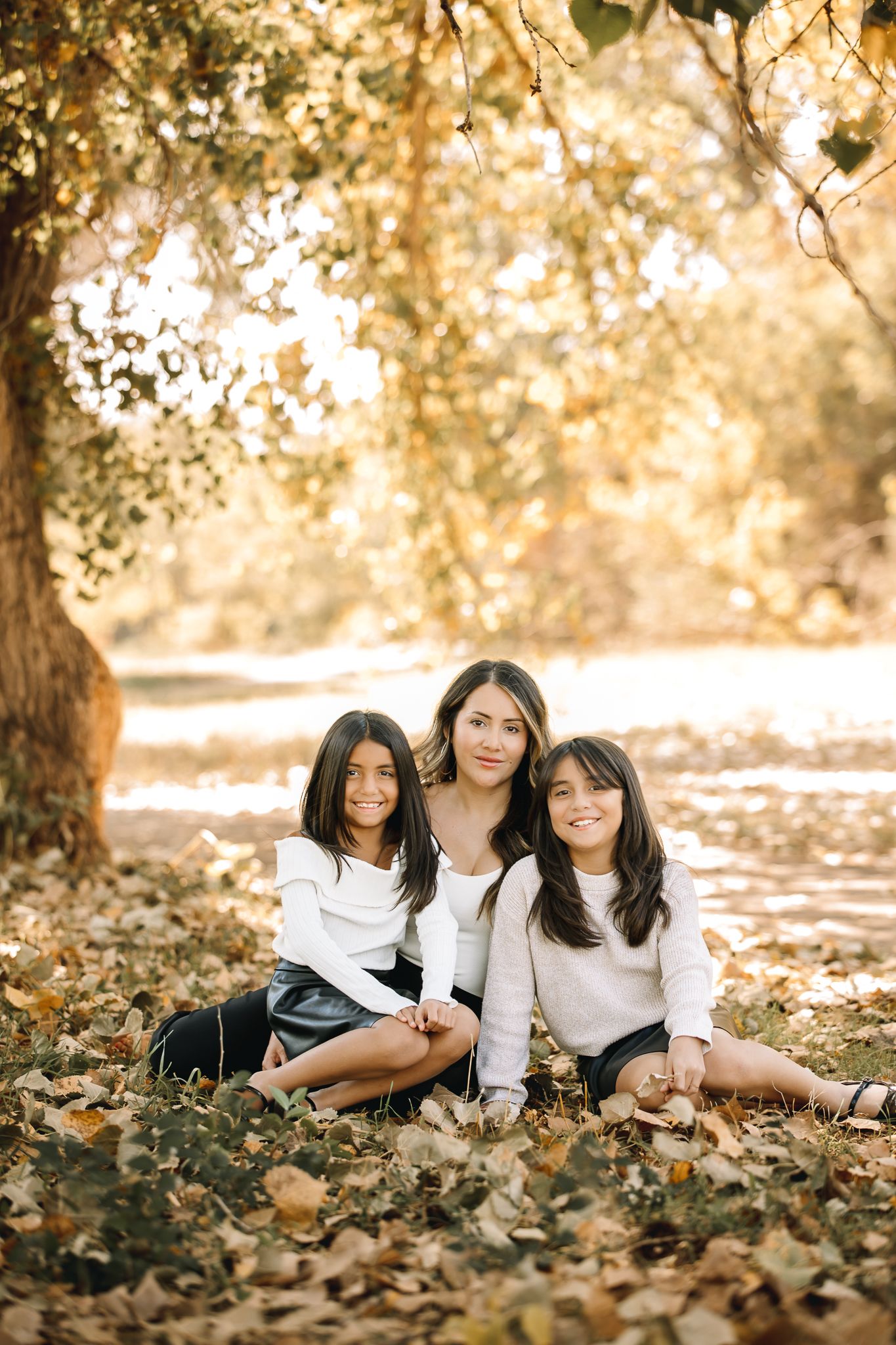 mother and her 2 yound daughts posing smiling at the camera in the fall time. liz rivas colorado photographer