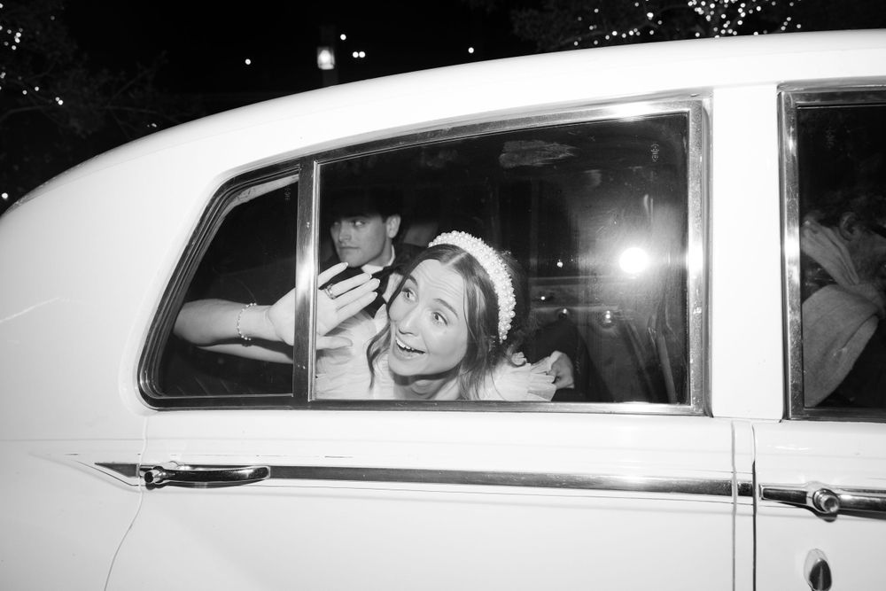 Vintage black and white photo showing a passenger smiling through a car window at night.