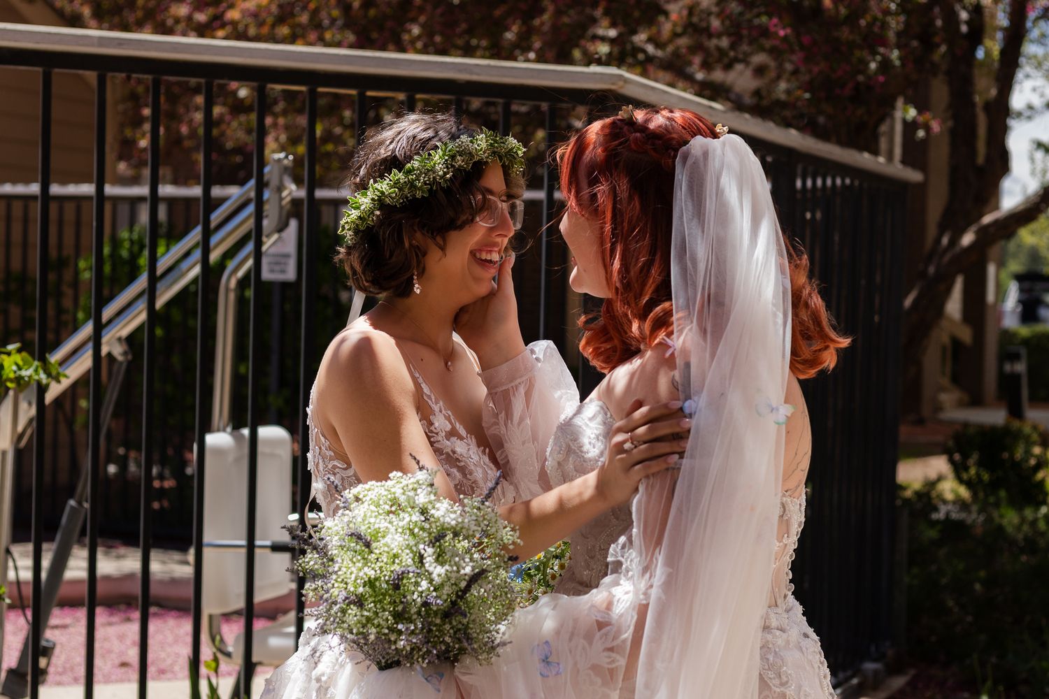 A tender moment between two brides in lace dresses on their wedding day.