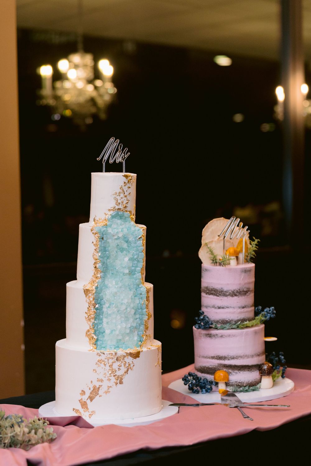 Elegant wedding cakes with blue and pink tiers decorated with gold accents and floral details.