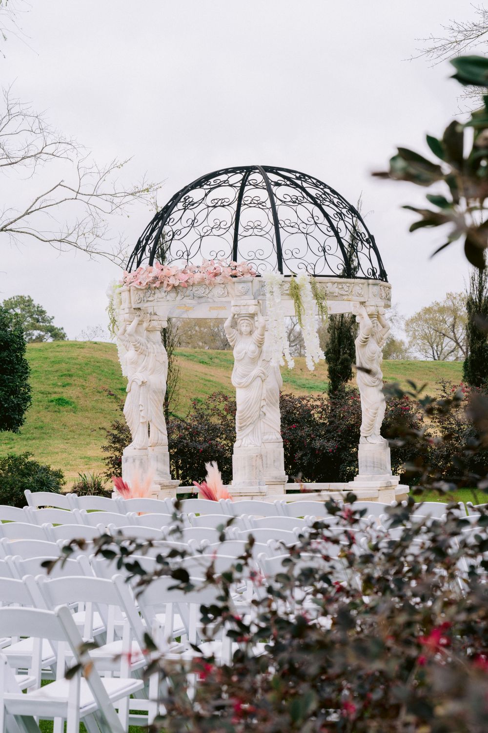 Romantic garden wedding gazebo with draped fabric and floral decorations against a misty backdrop.