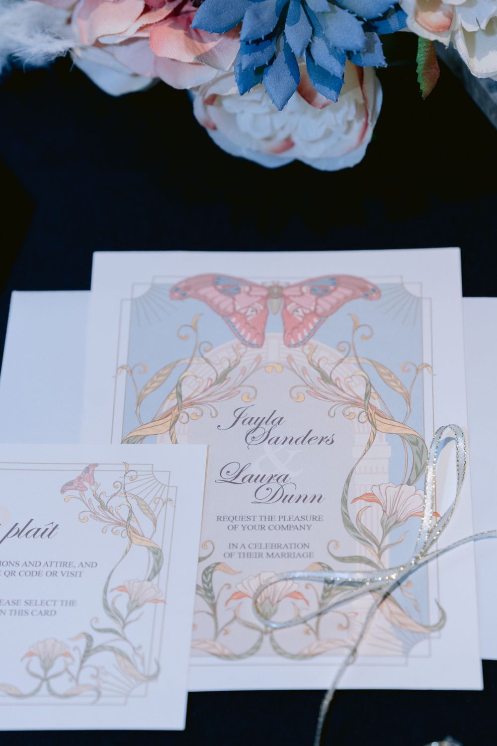Romantic wedding invitation with pink and blue floral design and elegant butterfly motif.