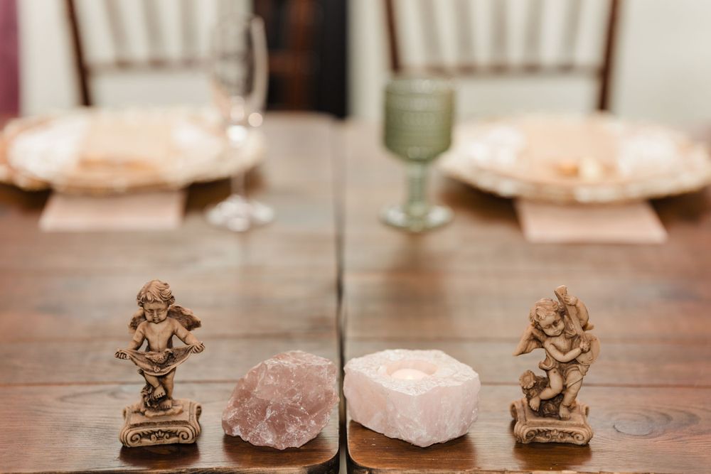 Table setting with crystal minerals and decorative bronze figurines on wooden surface.