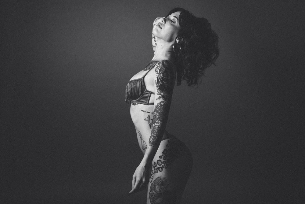 Black and white boudoir photo featuring vintage-style lingerie and dramatic lighting.