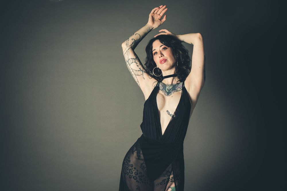 Artistic portrait of a model in lace and velvet with dramatic pose against dark background.