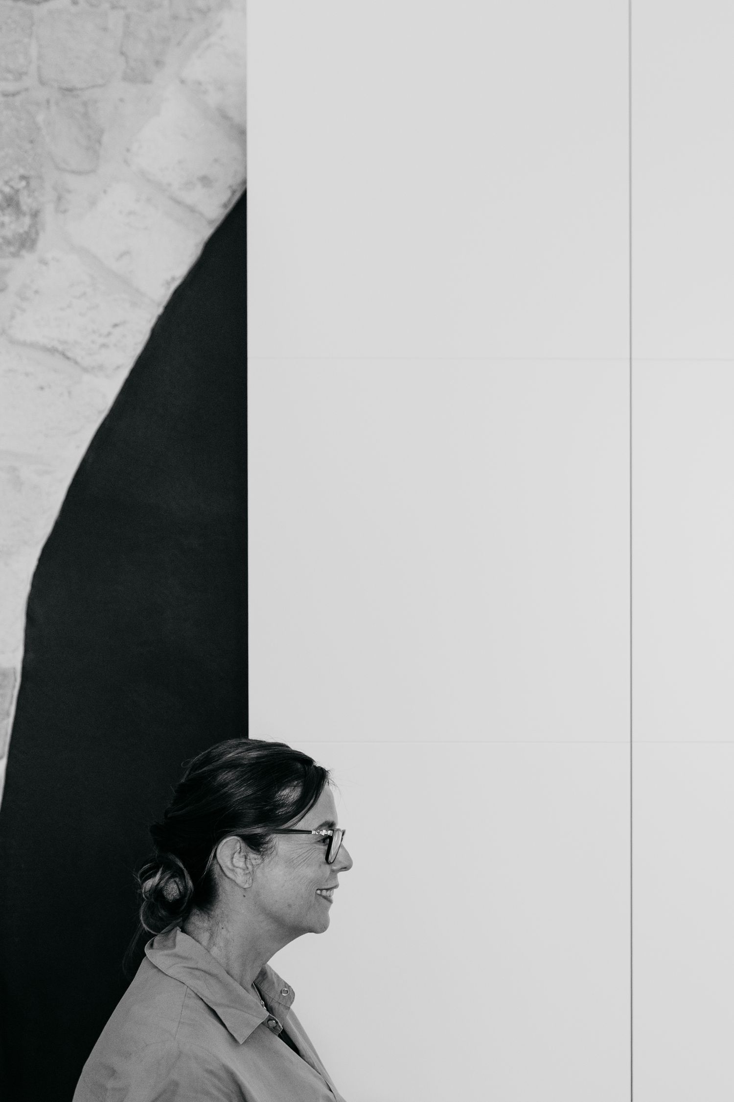 Black and white profile portrait of someone wearing glasses against a white and dark background.