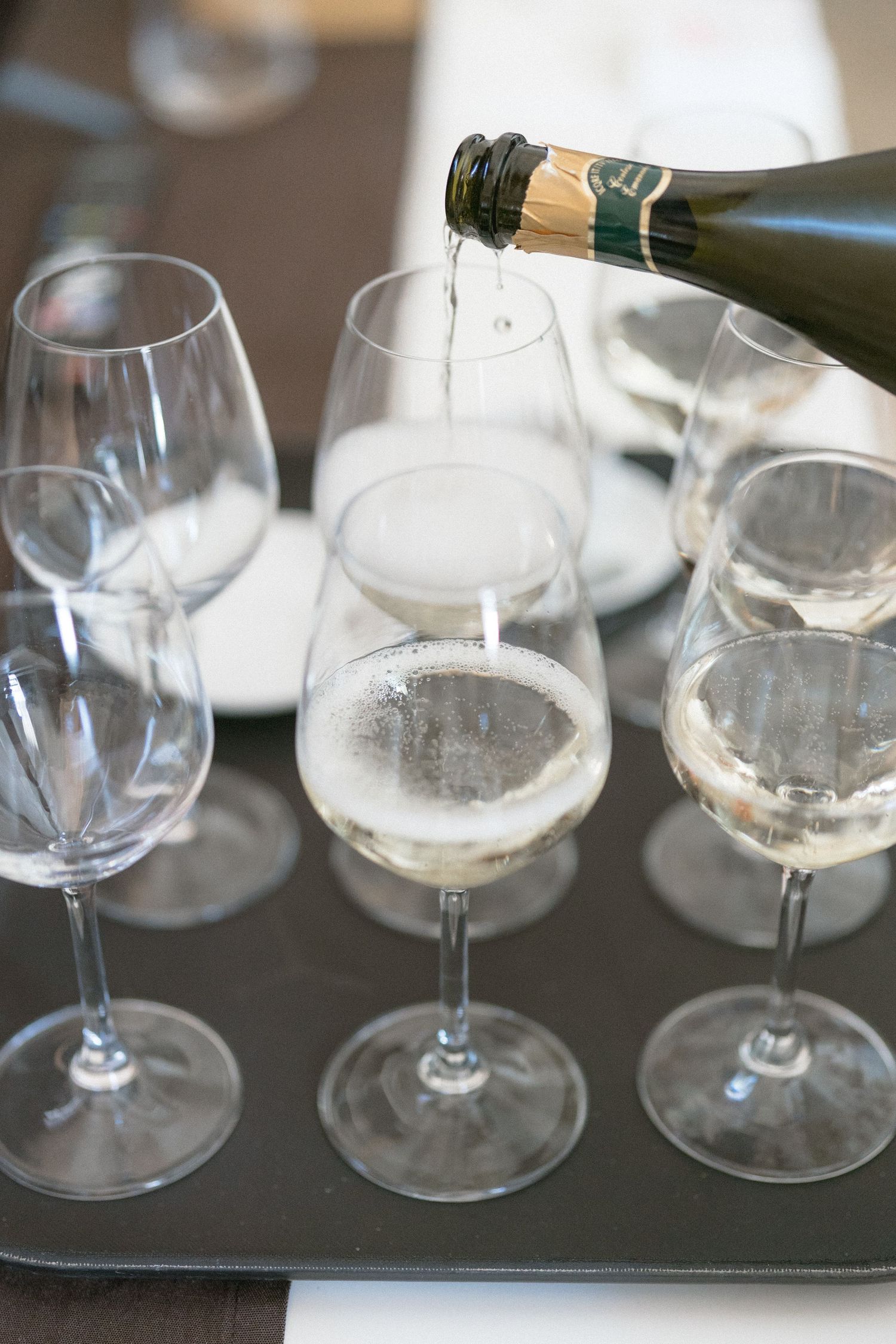 Multiple empty wine glasses arranged on a dark surface in a row.