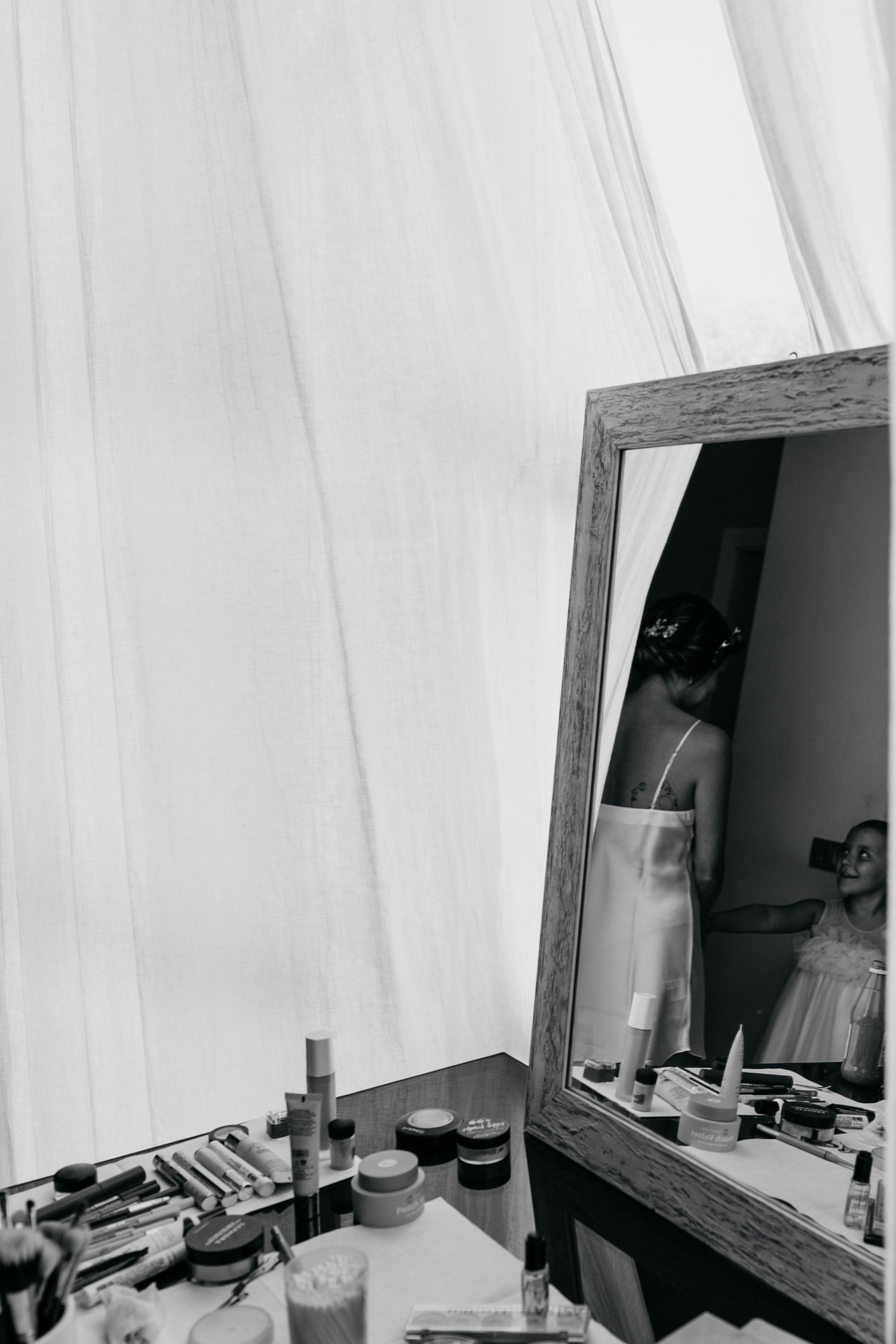 Interior shot of a dressing room with white curtains and a mirror showing preparation items.