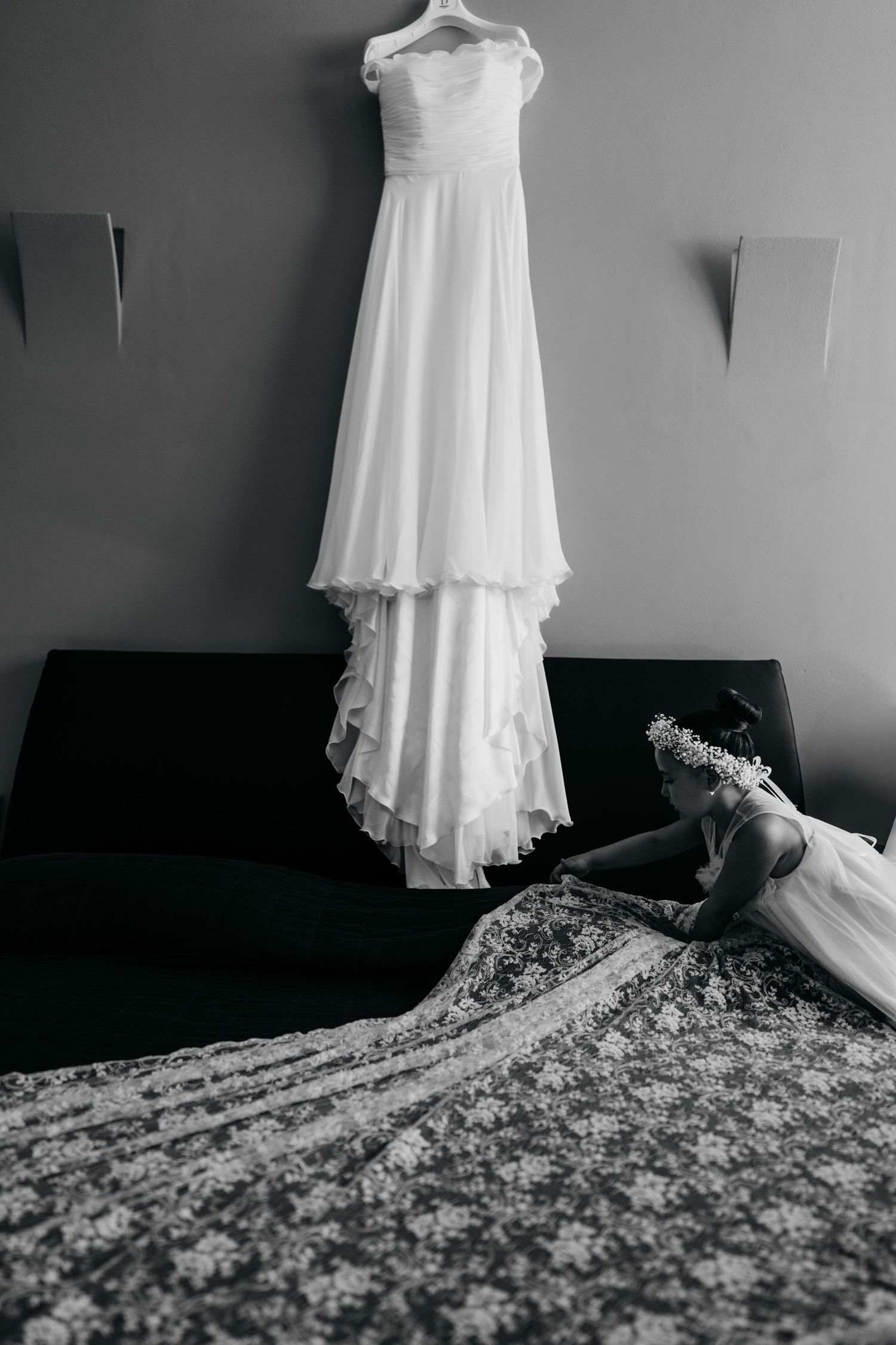 Classic white wedding dress hanging on display with delicate lace details in black and white.