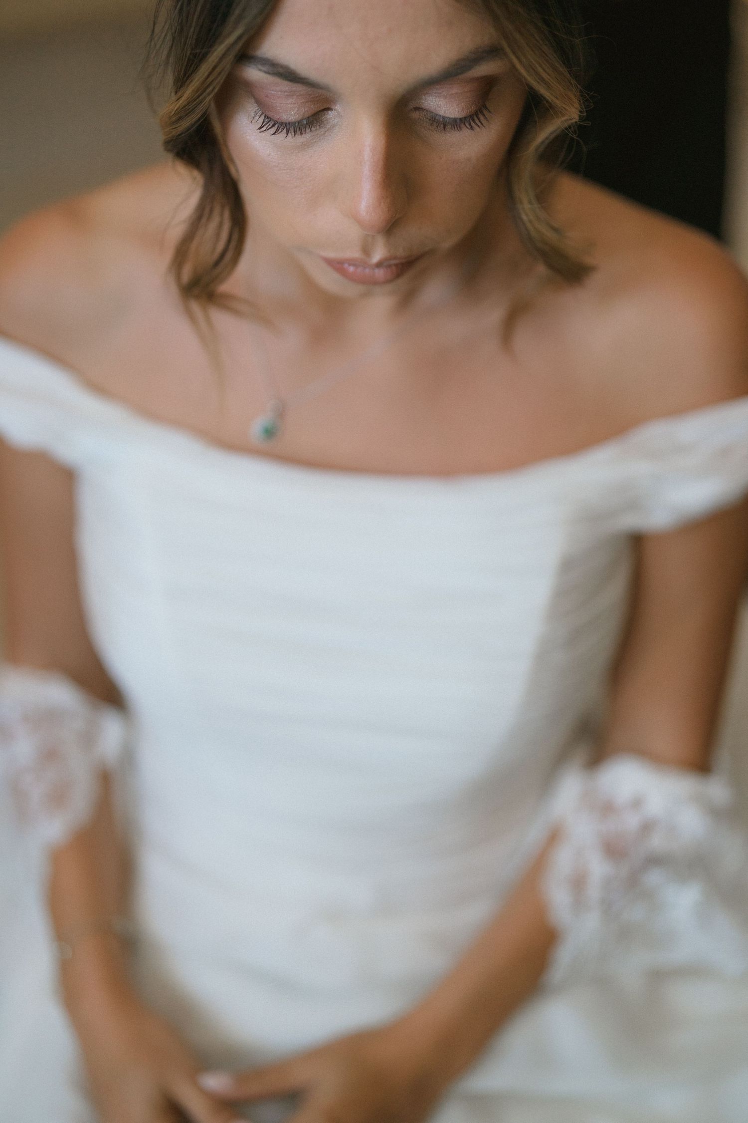 Close-up detail of an off-shoulder white wedding dress with delicate fabric and lace.