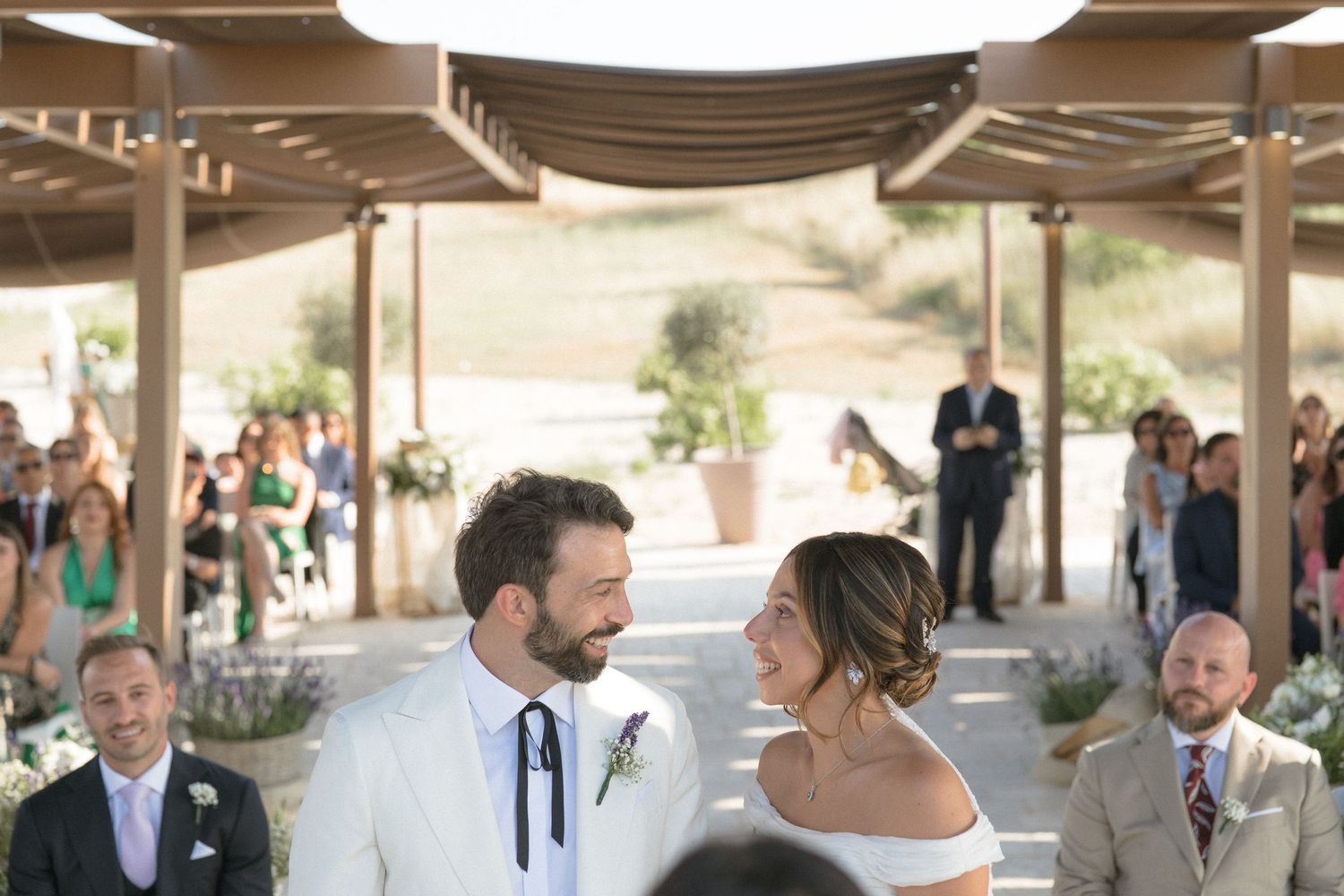 Newlyweds share a moment during their outdoor ceremony under a covered pavilion.