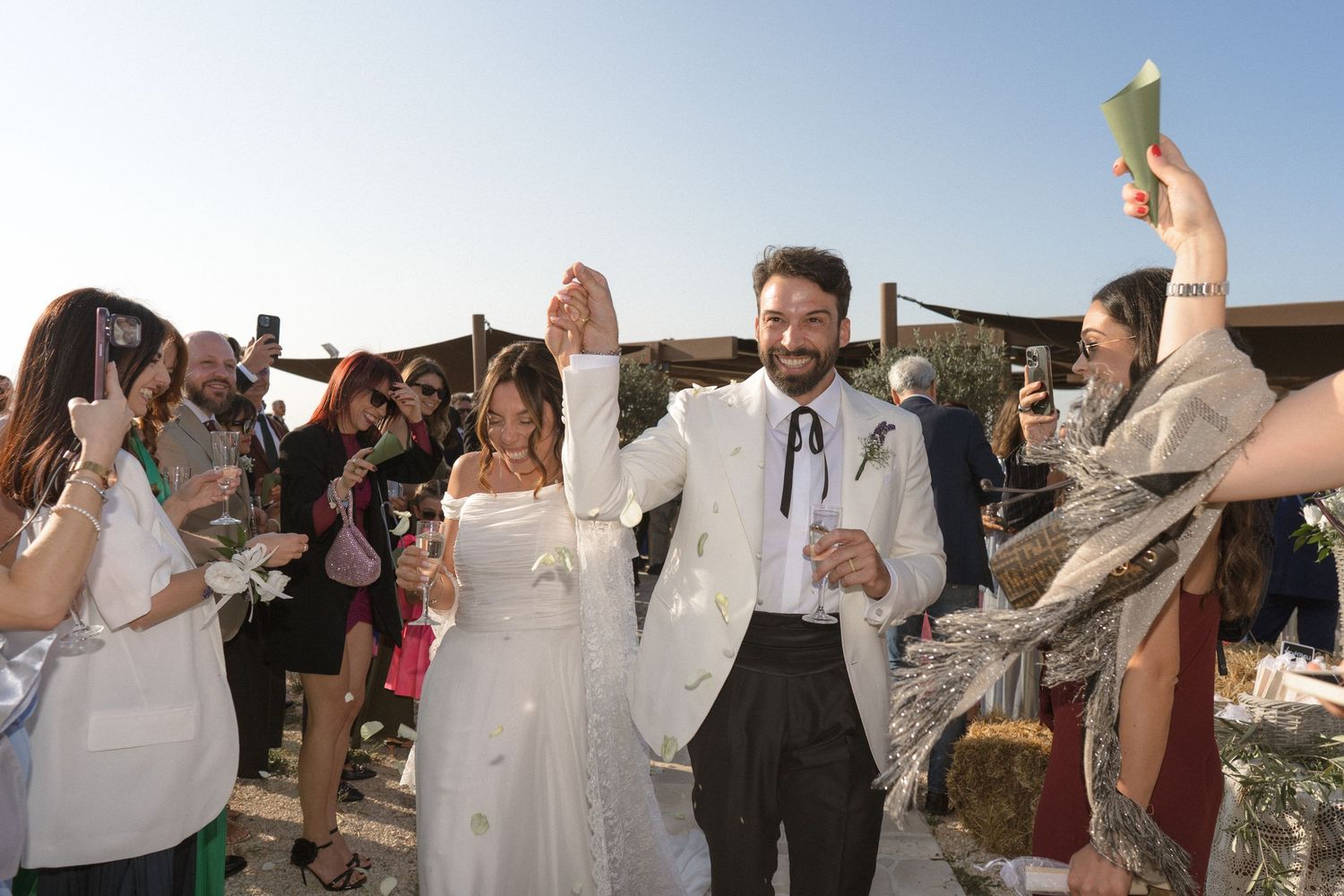 A group of wedding guests toasting with champagne glasses during an outdoor celebration.