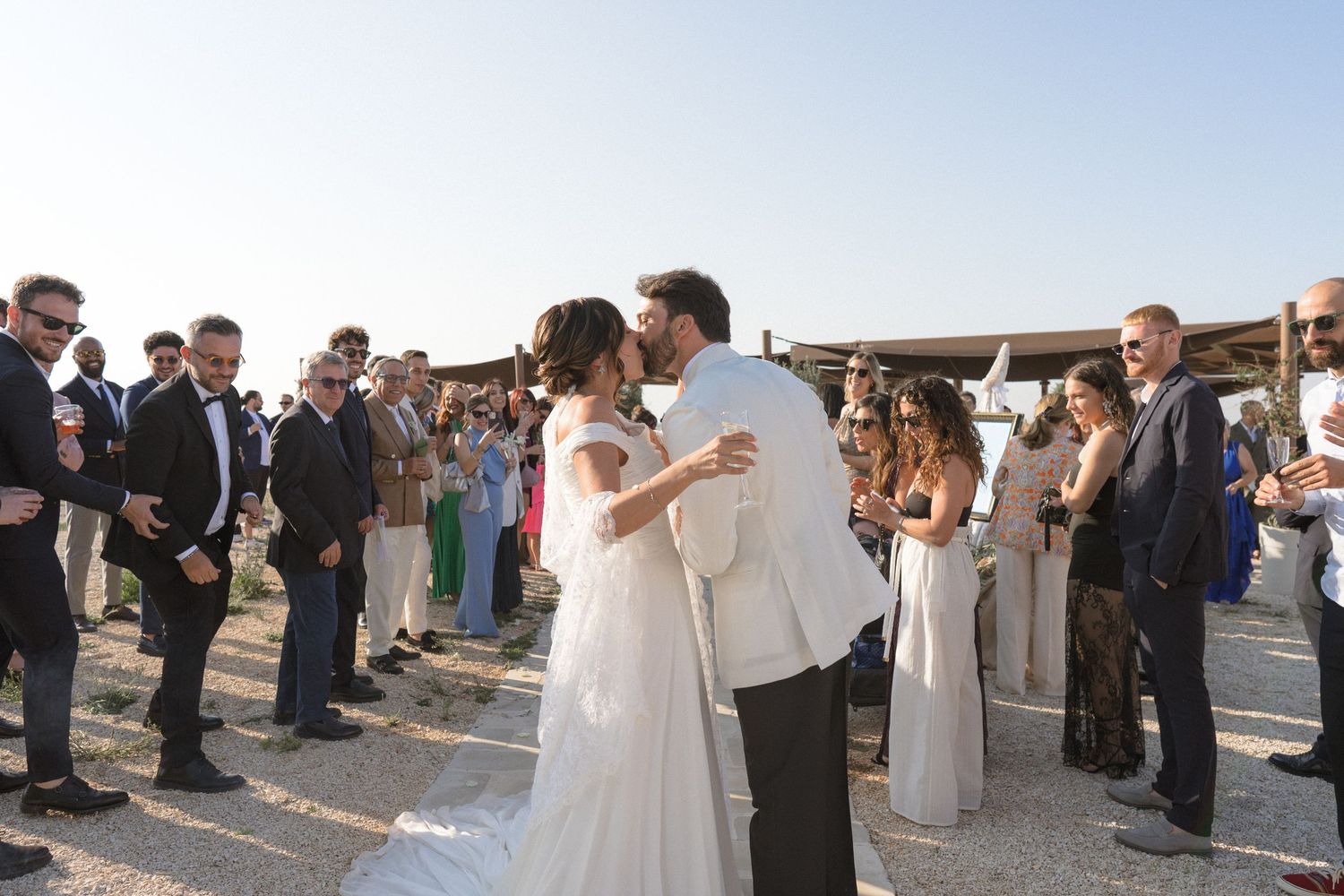 Panoramic view of an outdoor wedding ceremony with guests gathered under a wooden structure.