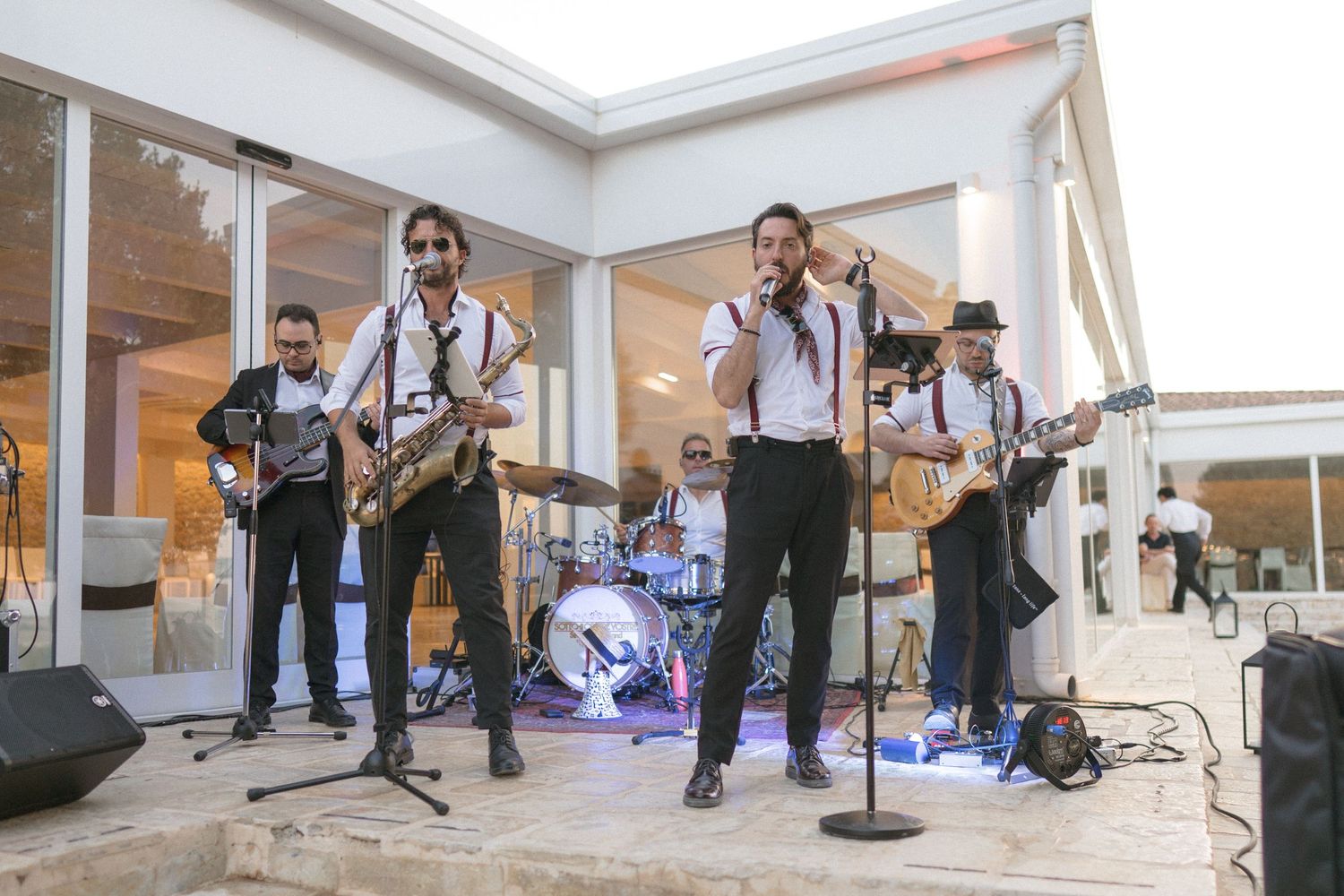 A lively band performs on an outdoor stage with musicians playing instruments and singing.