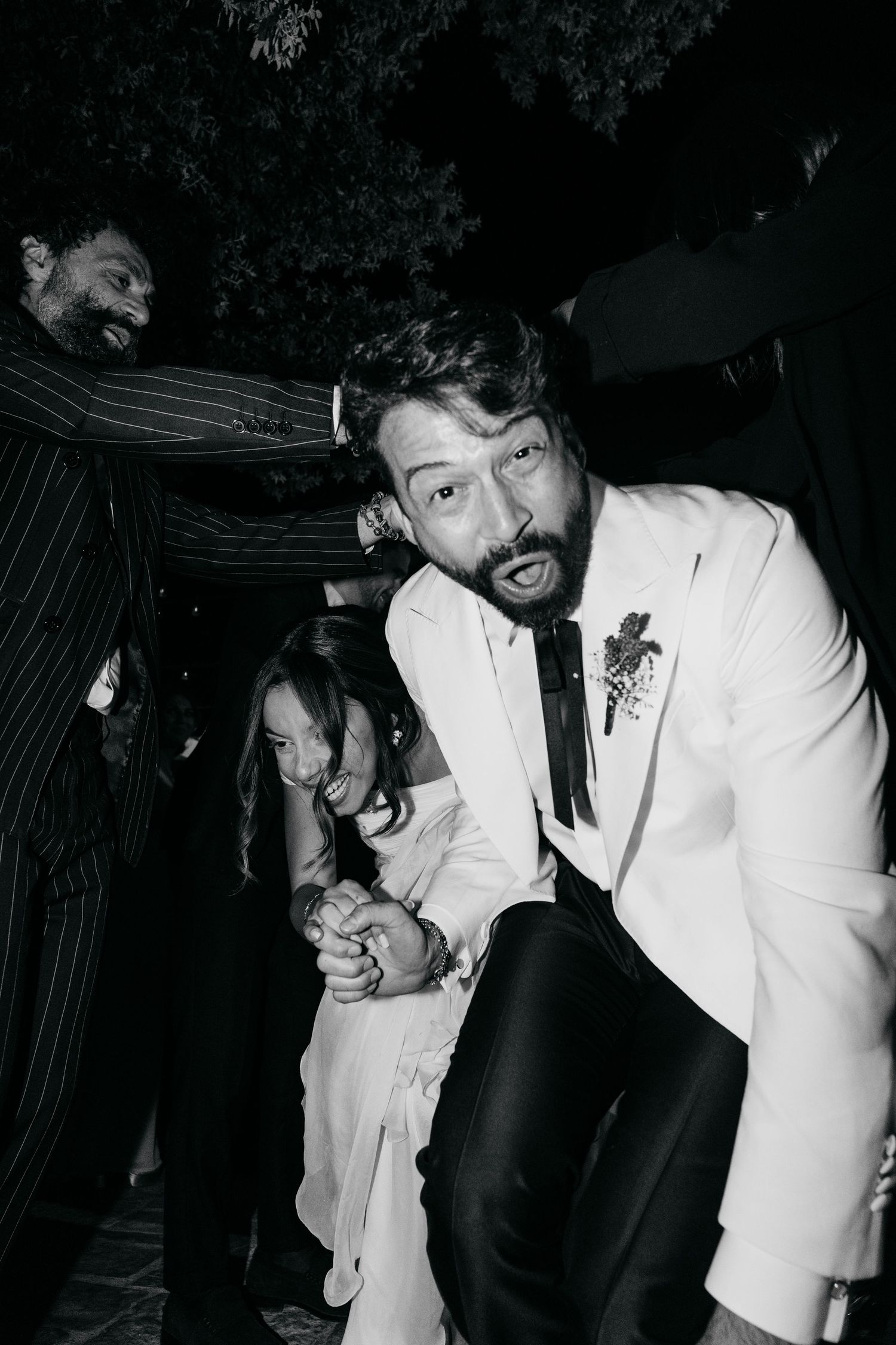 A lively moment at a formal event with guests in elegant attire captured in black and white.