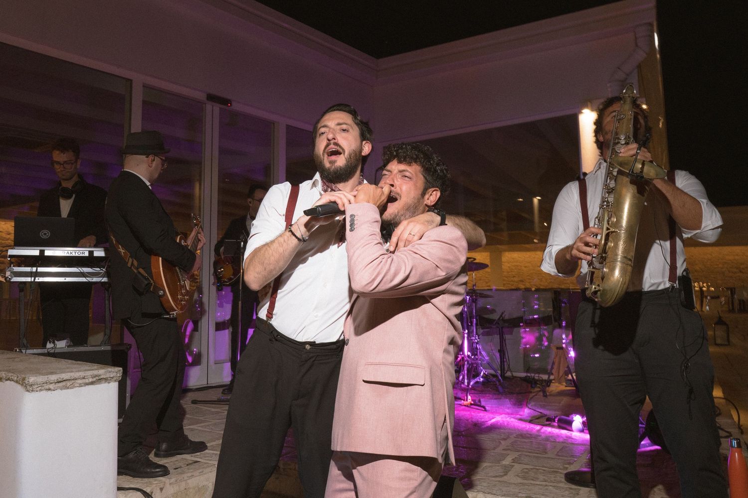 Two performers singing passionately on stage during a wedding reception.
