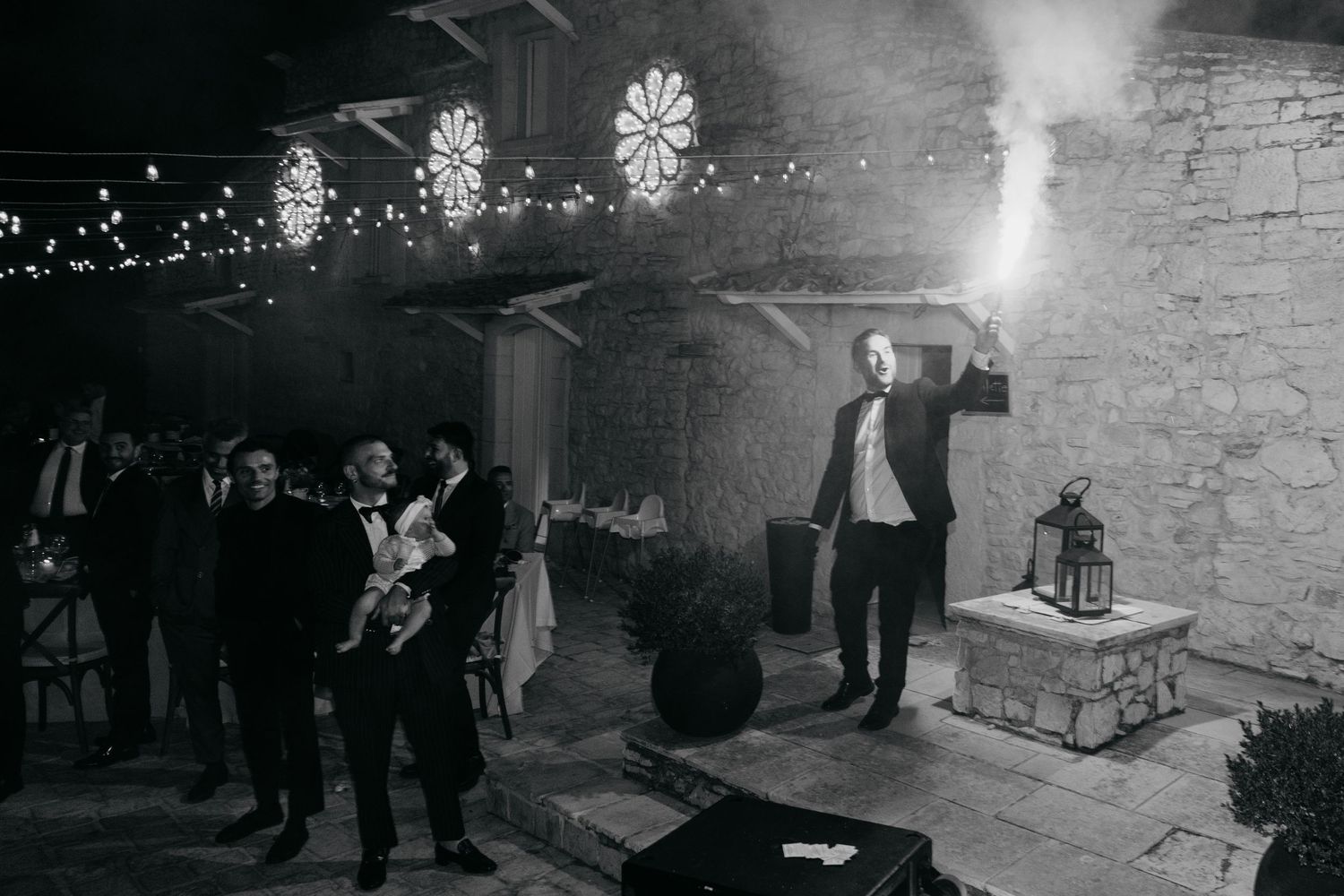 Night celebration with sparklers illuminating the stone exterior of a venue.