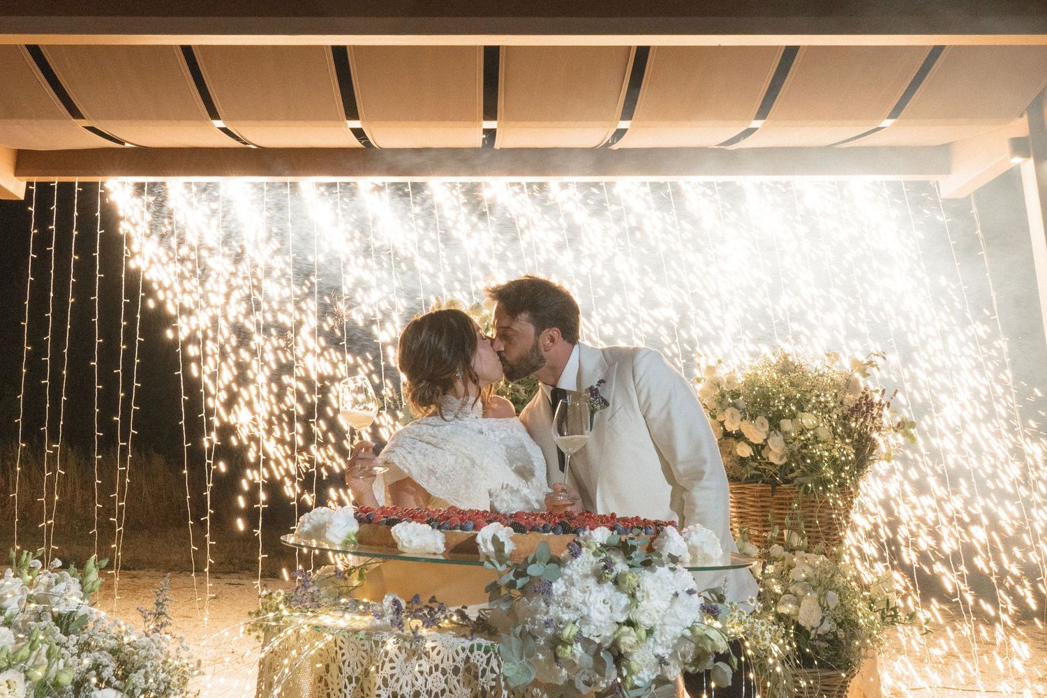 Couple sharing a romantic moment under cascading sparkler fountains during wedding reception celebration.