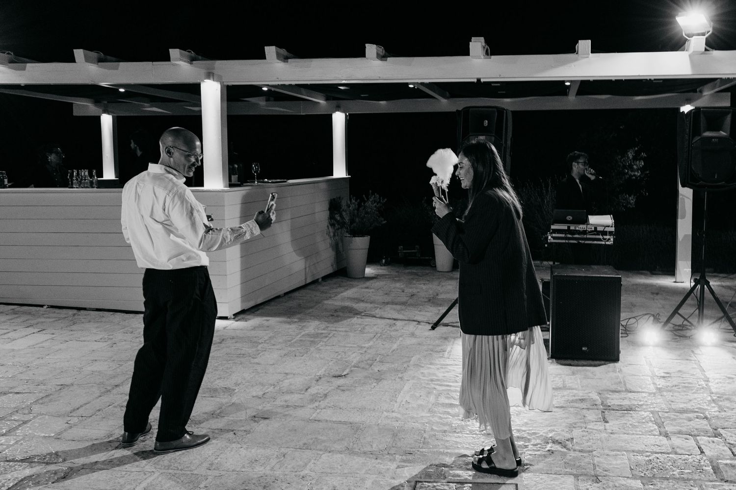 A couple dancing together during an outdoor evening celebration in black and white.
