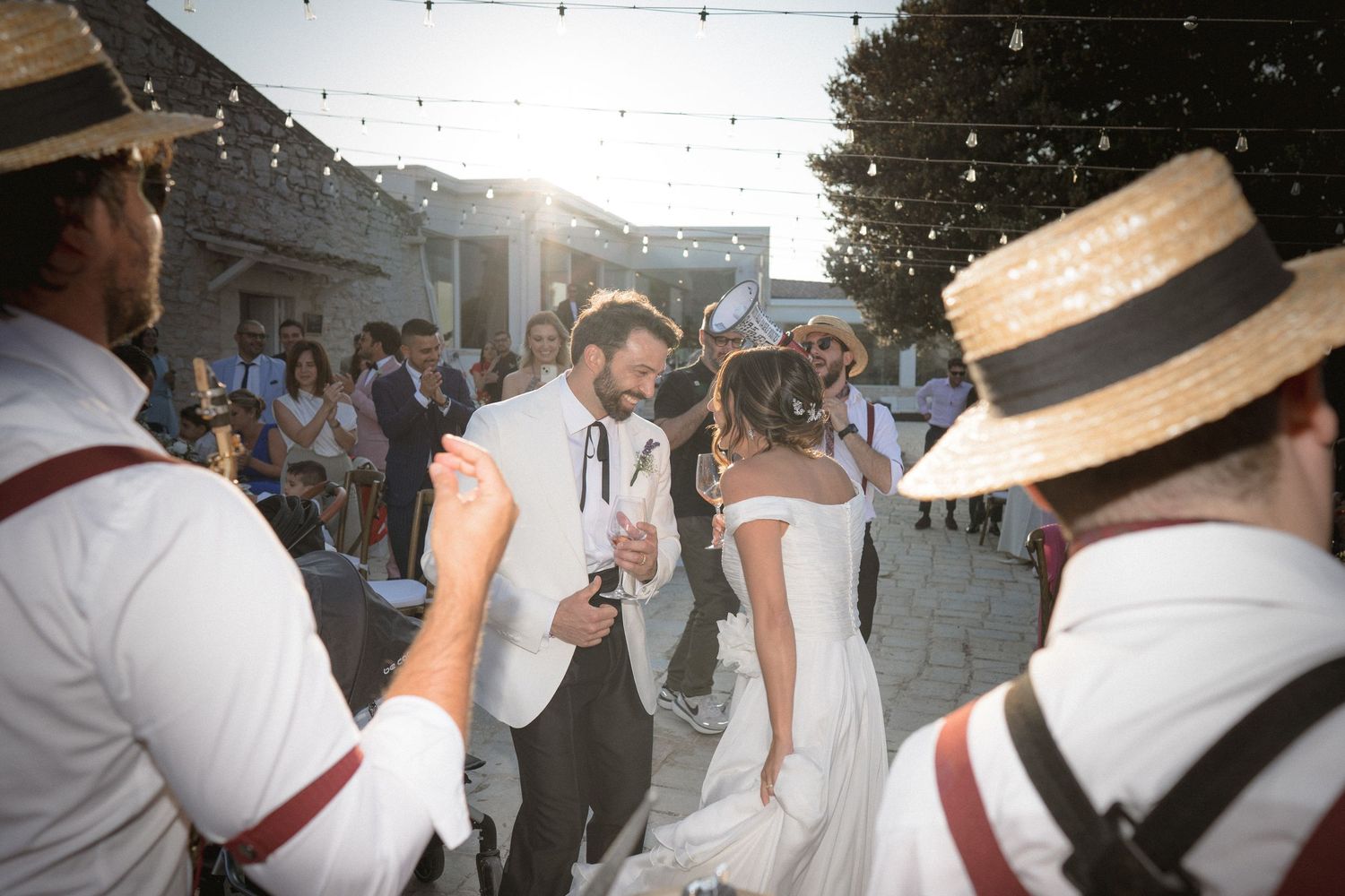 Dancing and celebration at an outdoor party with guests wearing straw boater hats.