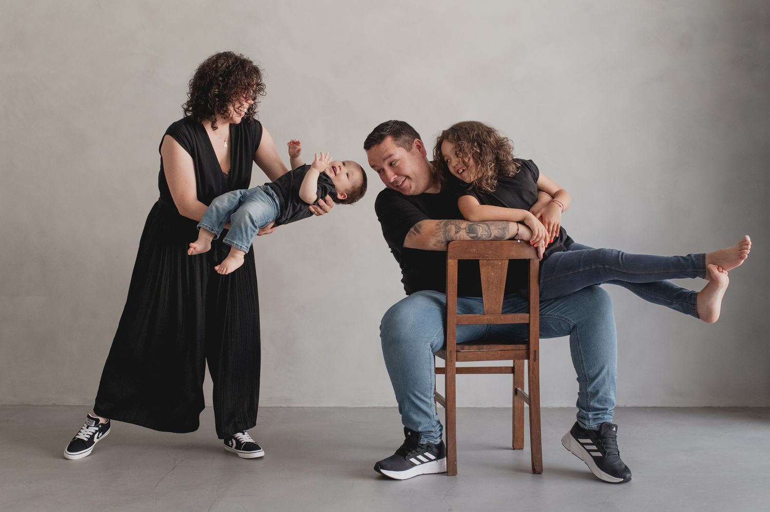 Series of playful poses between two people on wooden chairs against a gray wall.