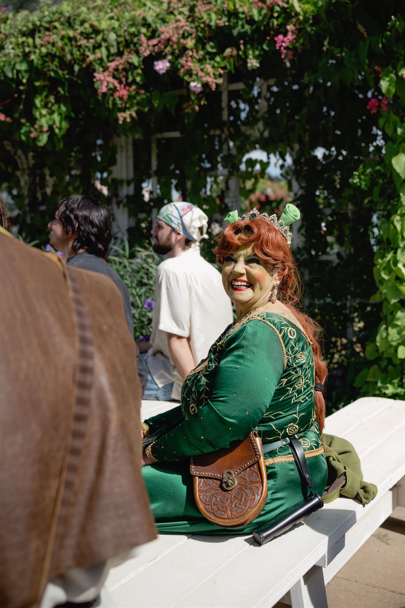 Six sequential images showing a woman in a green dress sitting on a white bench outdoors, laughing joyfully in a garden setting.