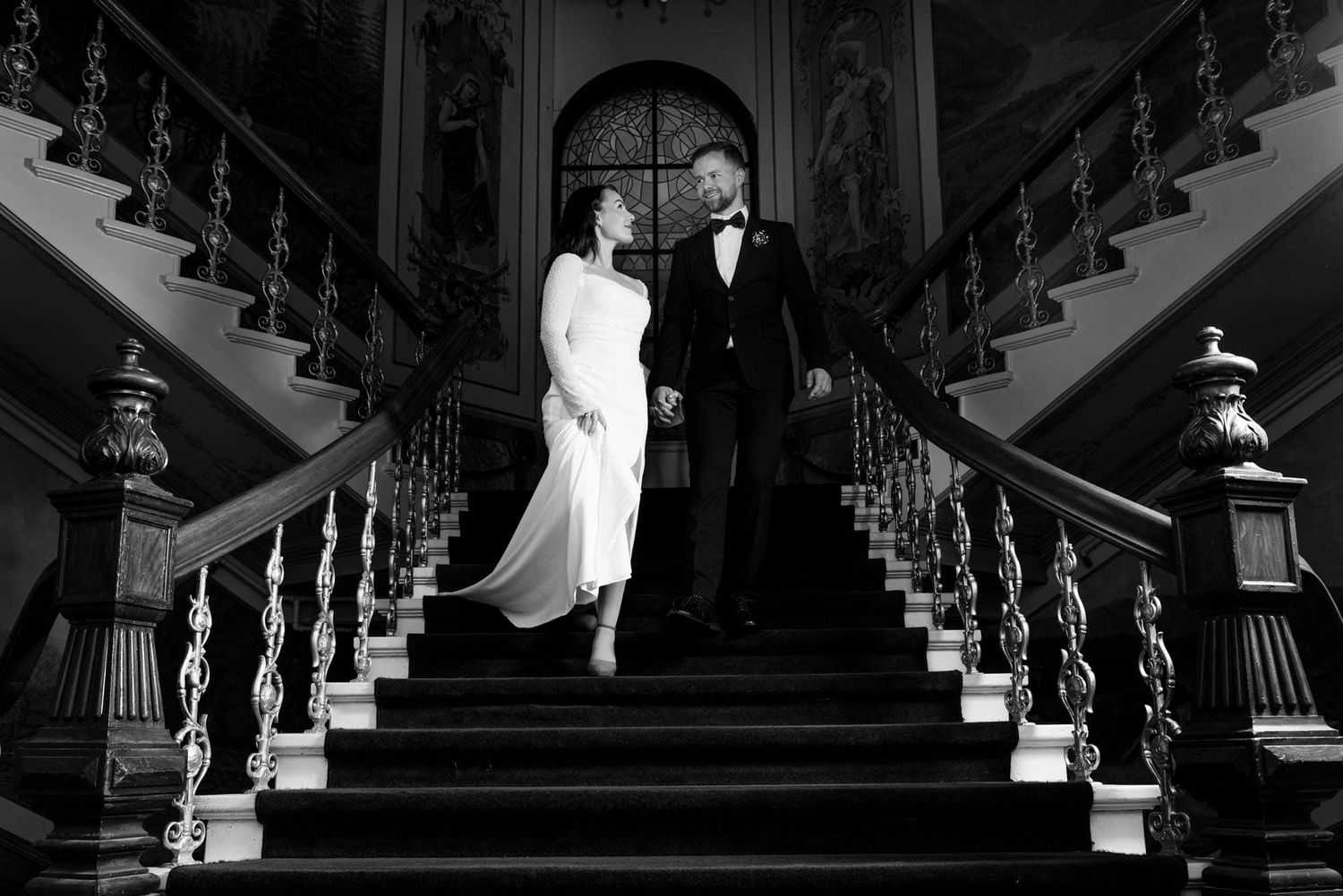 Stilig brudepar som står mildt i en kul trapp og ser på hverandre på en bryllupsfotografering på Ernst Hotel i Kristiansand
