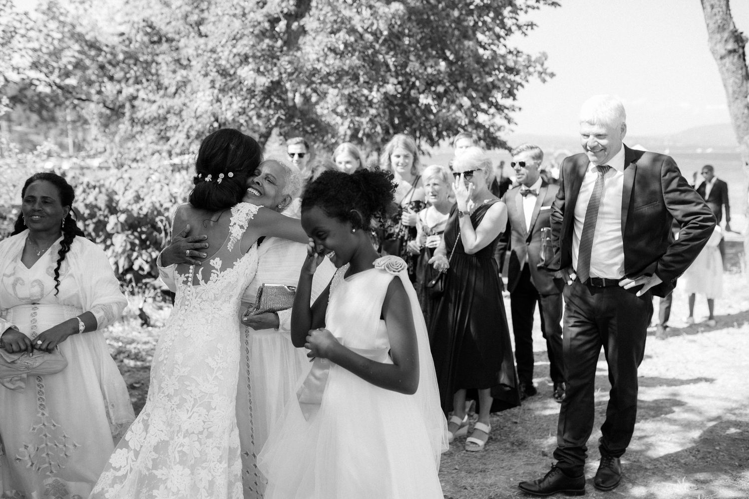 Wedding guests gather outside on a sunny day during a celebration.