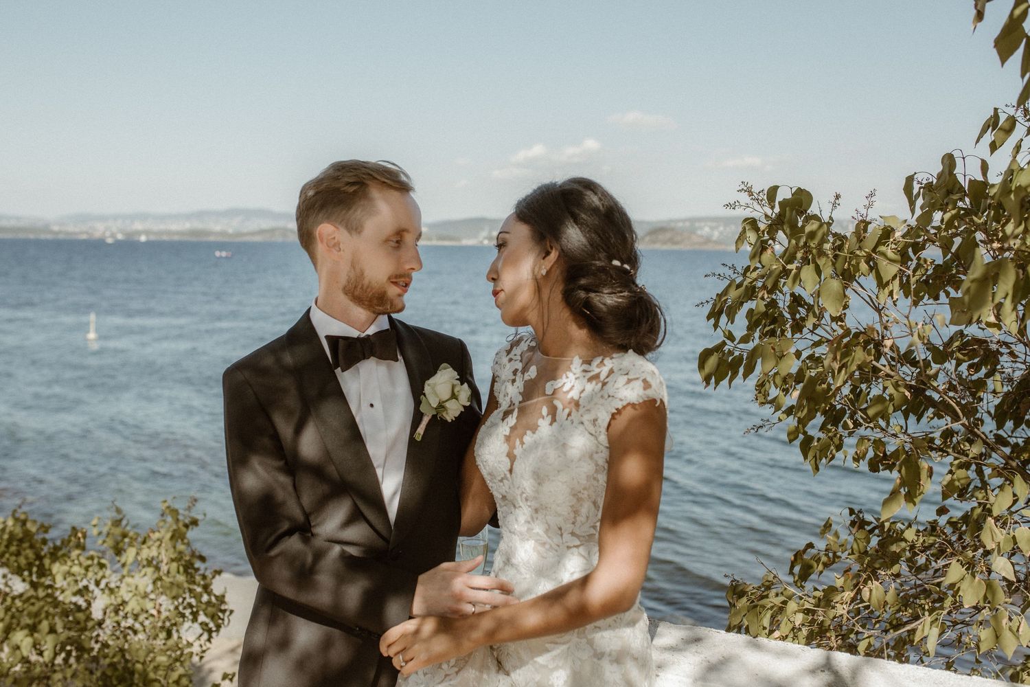 Newlyweds share an intimate moment by the waterfront on their wedding day.