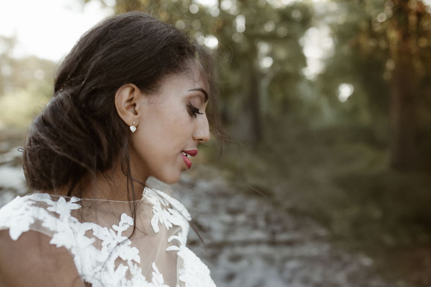 Side profile view of a bride wearing an elegant lace wedding dress and delicate earrings.