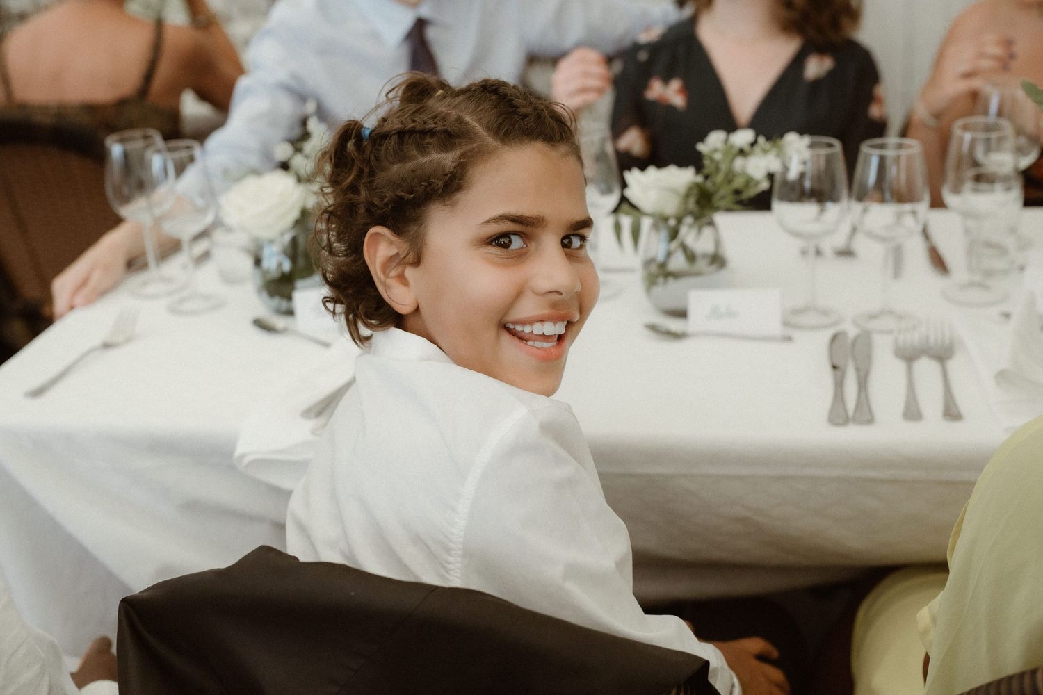 Guest seated at elegant wedding reception table with white linens and floral centerpieces.