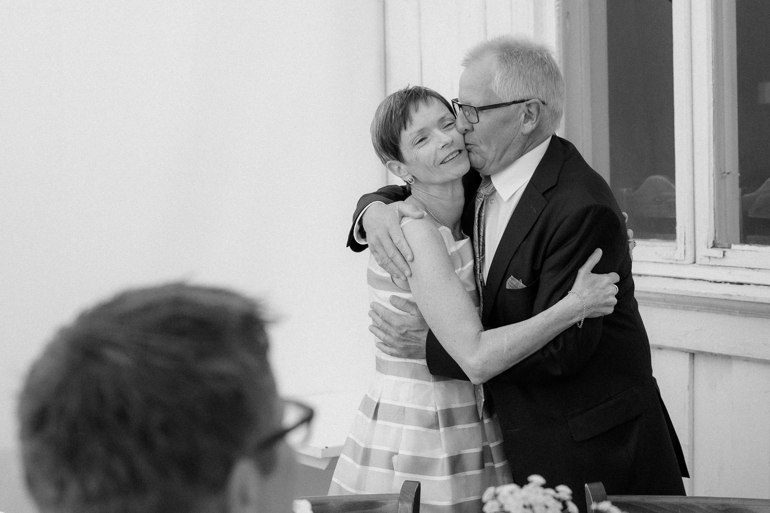 A tender moment between a couple in formal attire sharing an embrace at a wedding reception.