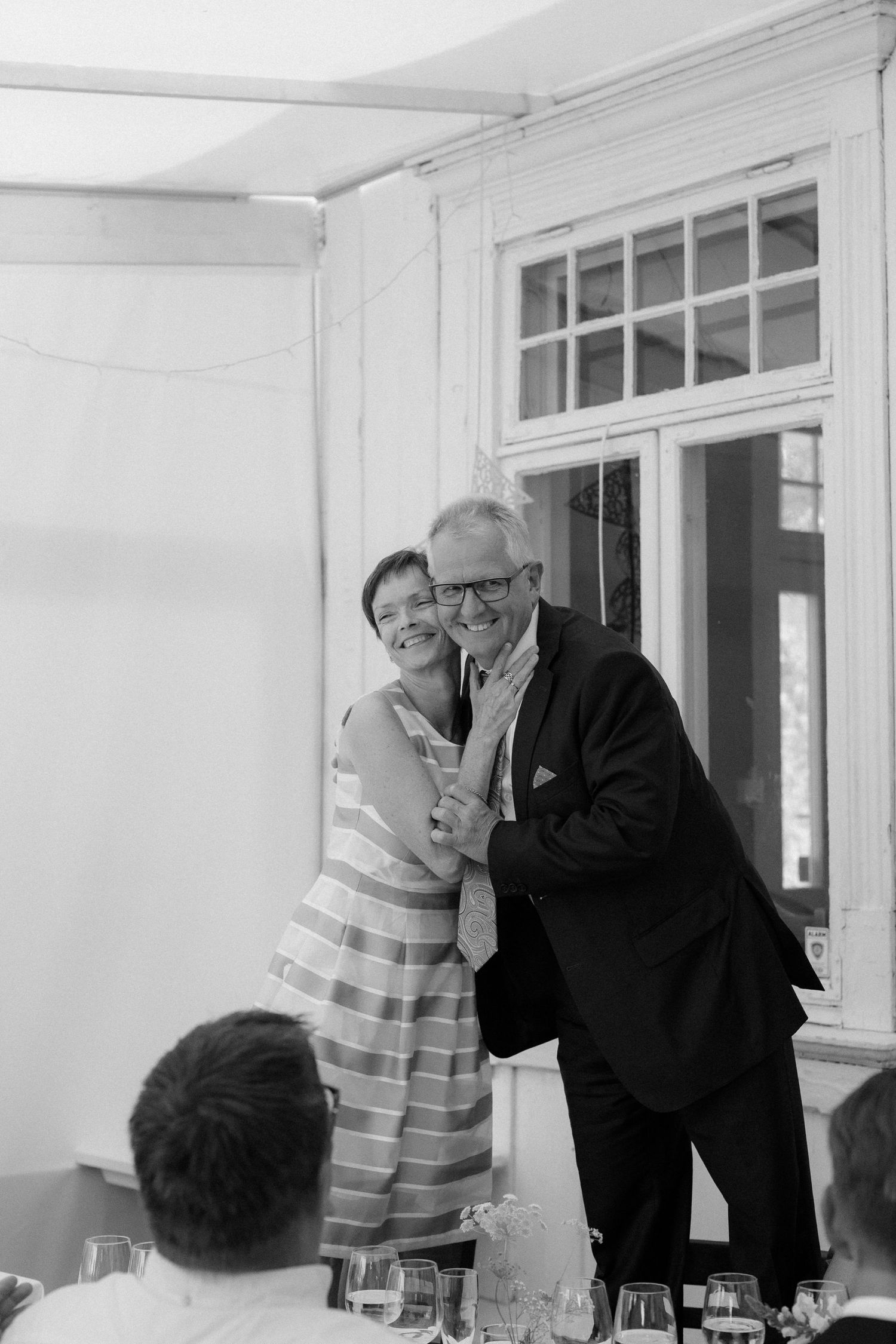 A couple sharing a joyful moment while standing at their reception table.