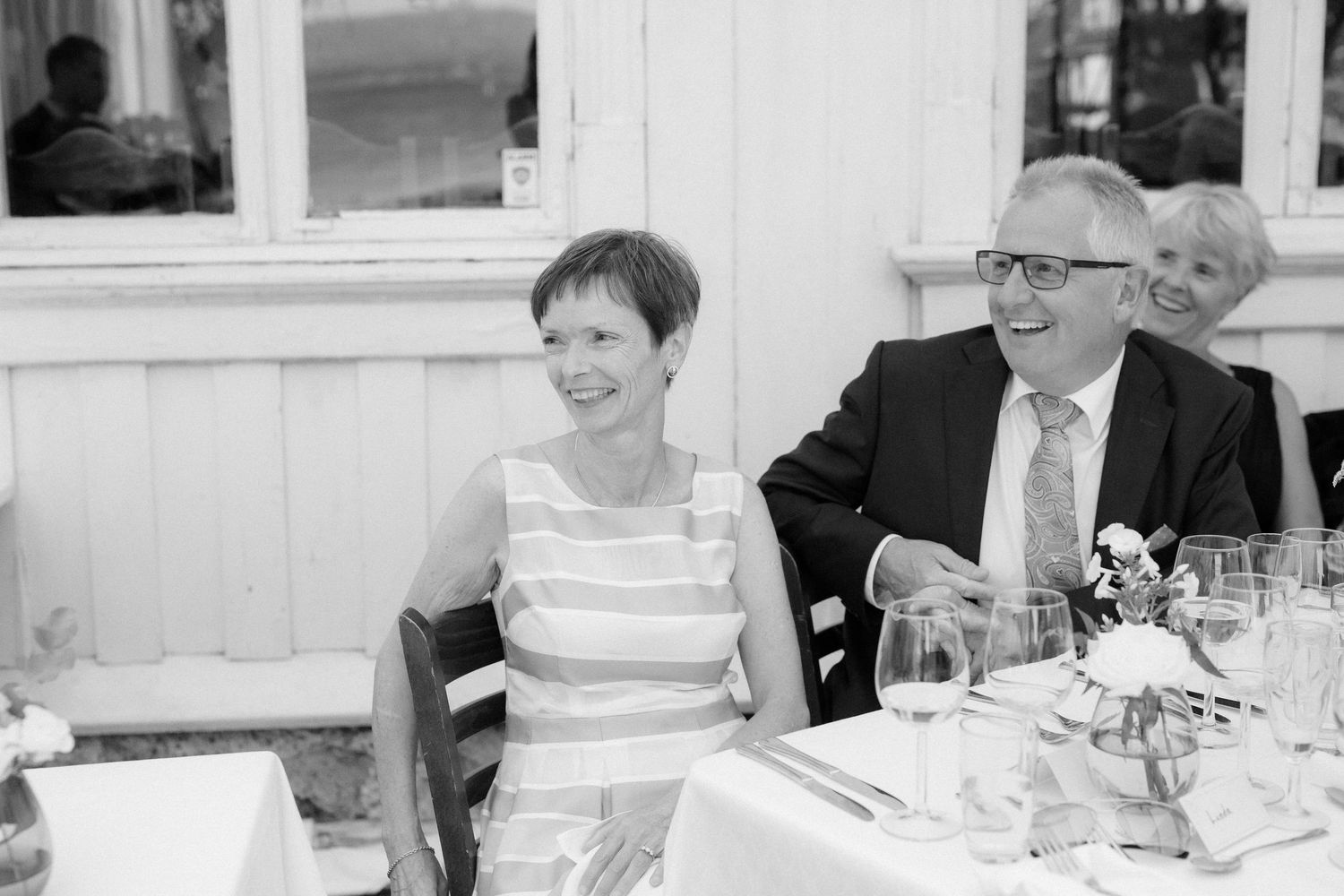 A couple seated at their wedding reception table share a candid moment together.