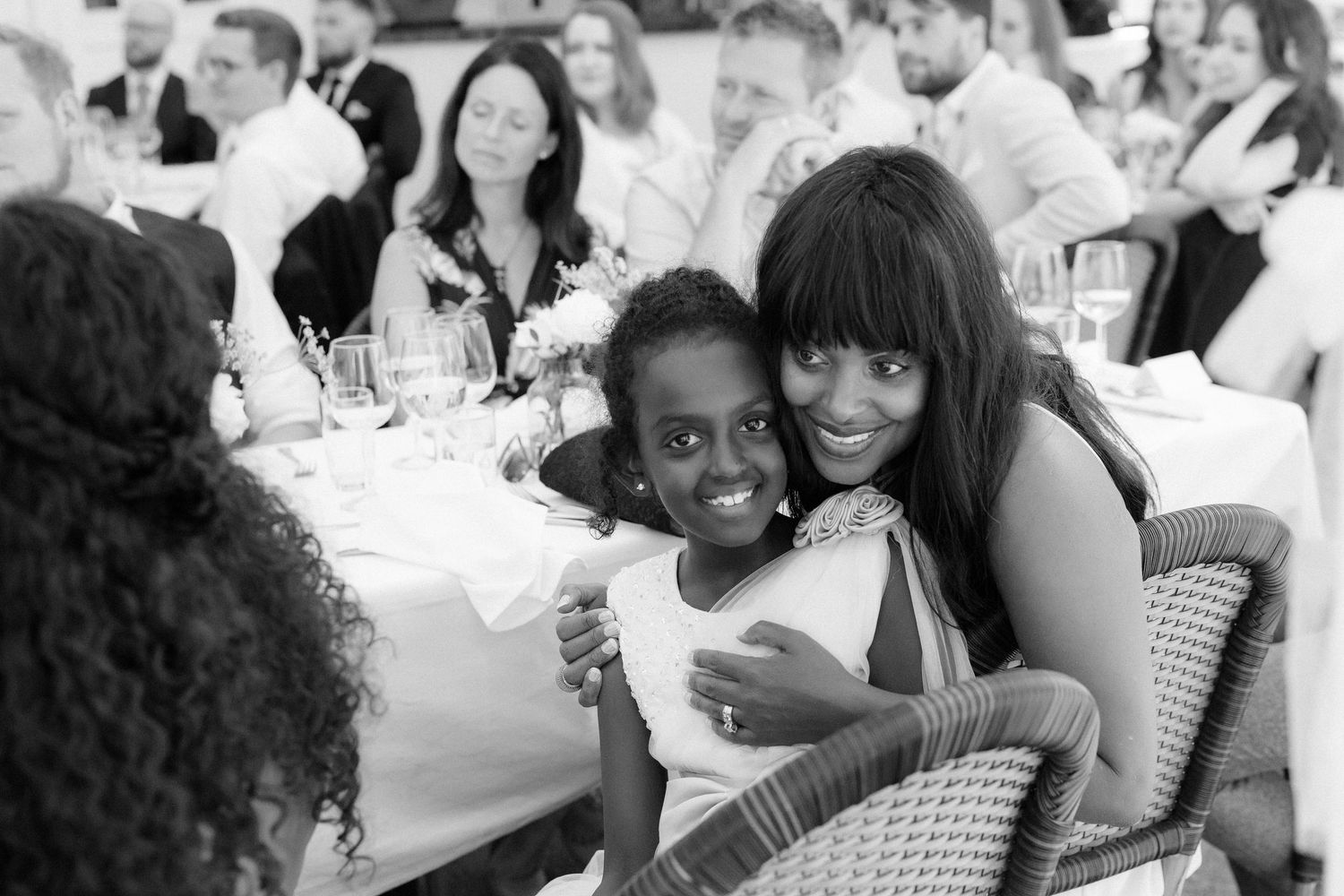 Candid black and white photo of guests sharing joyful moment at wedding reception.