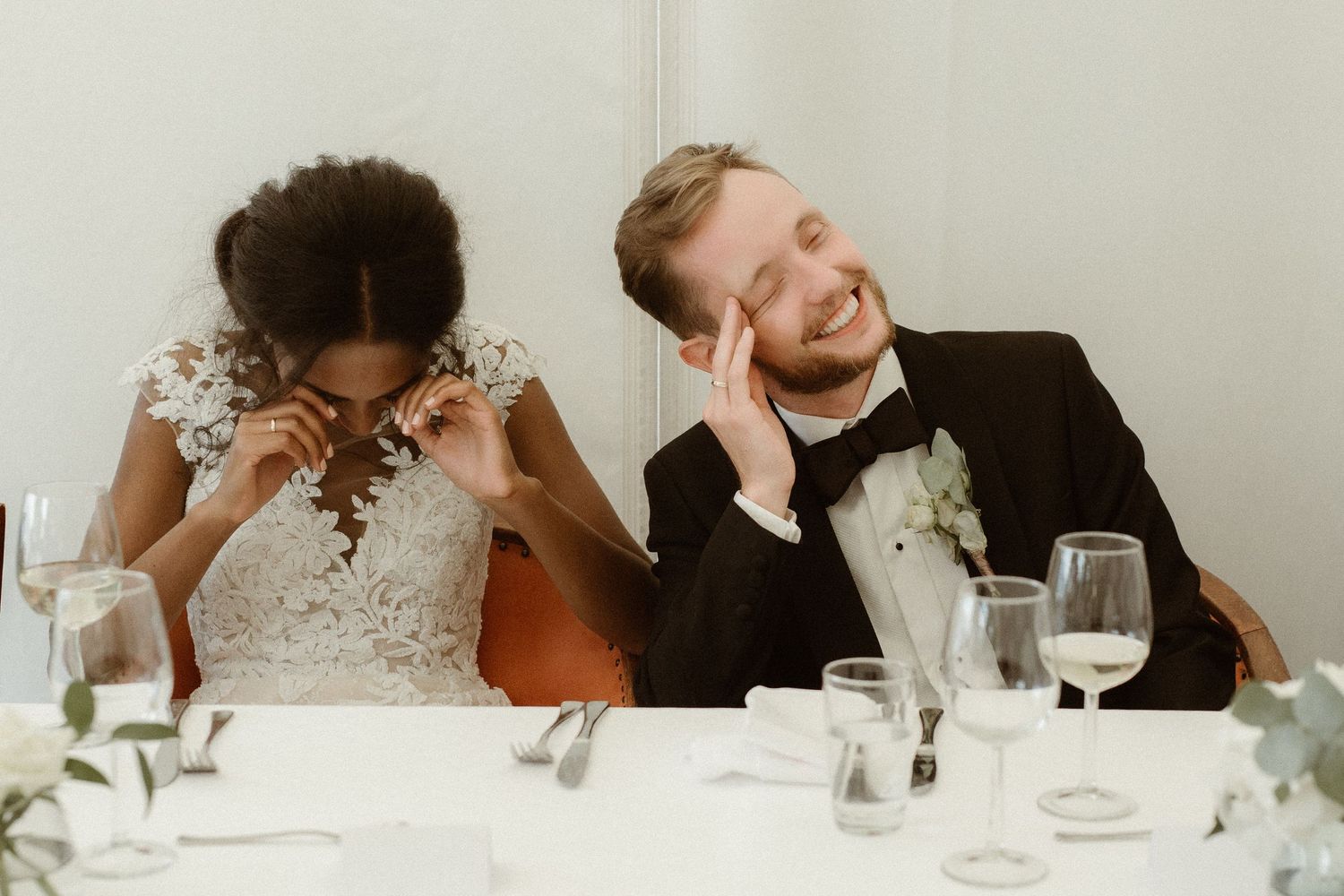 Candid moment of couple sharing laughter during wedding reception dinner.