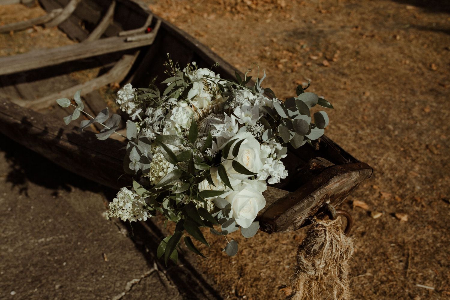 A delicate white floral bouquet rests on a rustic wooden surface in natural lighting.