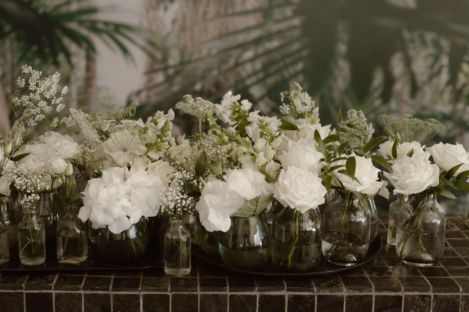 White floral centerpieces arranged in glass vases creating an elegant wedding table display.