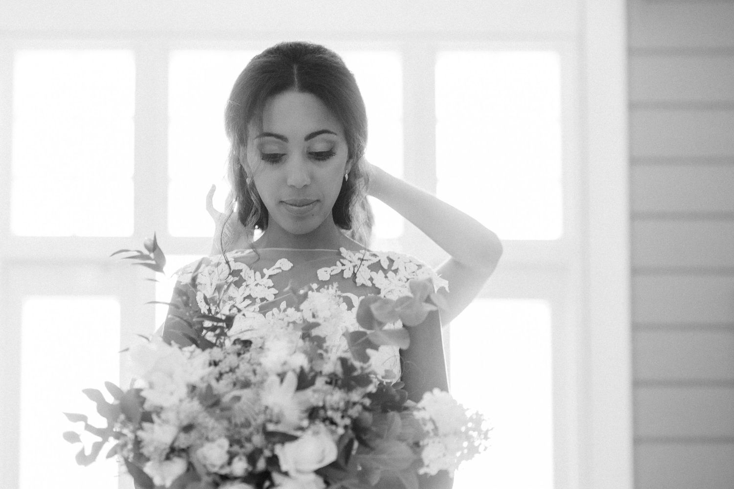 Bride with delicate florals poses in ethereal window light wearing romantic wedding gown.