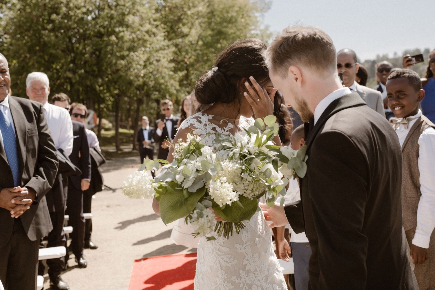 A tender moment between newlyweds during their outdoor wedding ceremony surrounded by guests.