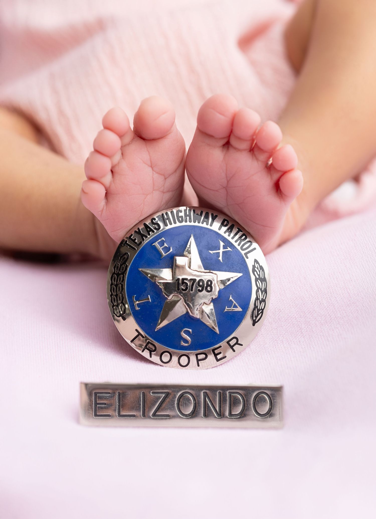 Close-up view of a baby's tiny bare feet with a vintage camera on cream-colored fabric.