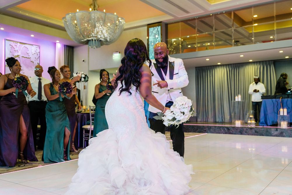 A couple shares their first dance at a wedding reception in an elegant ballroom with a crystal chandelier overhead.