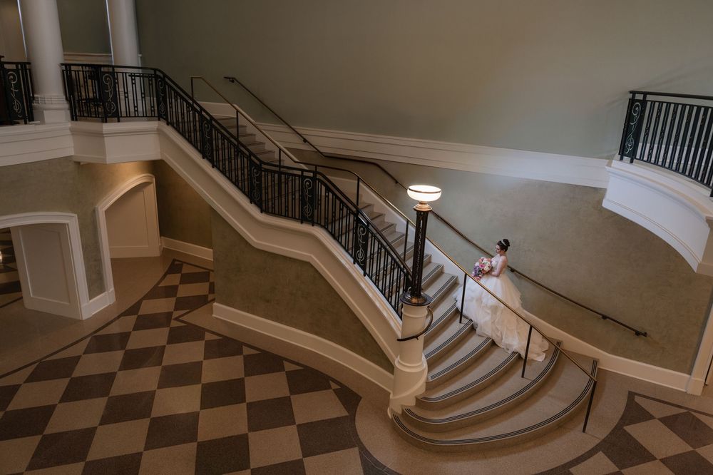 Elegant curved staircase with checkered flooring and black metal railings in a contemporary interior space.
