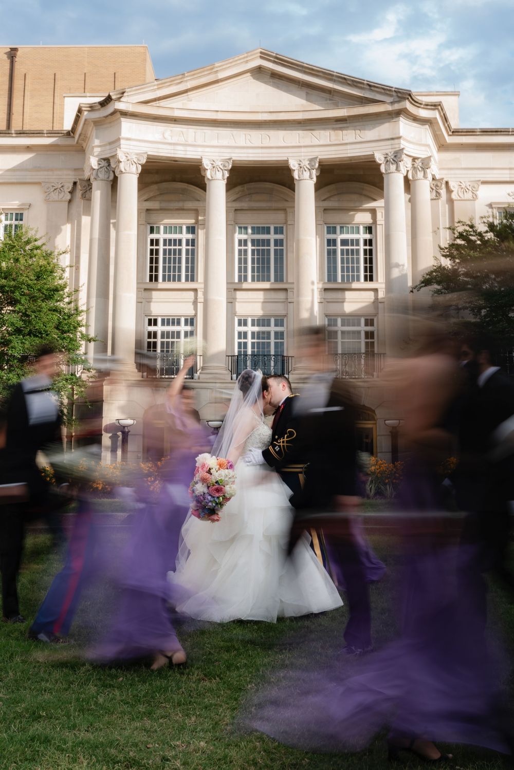 Wedding party in motion creates blurred purple effect in front of elegant classical building with white columns and pediment. Charleston, SC